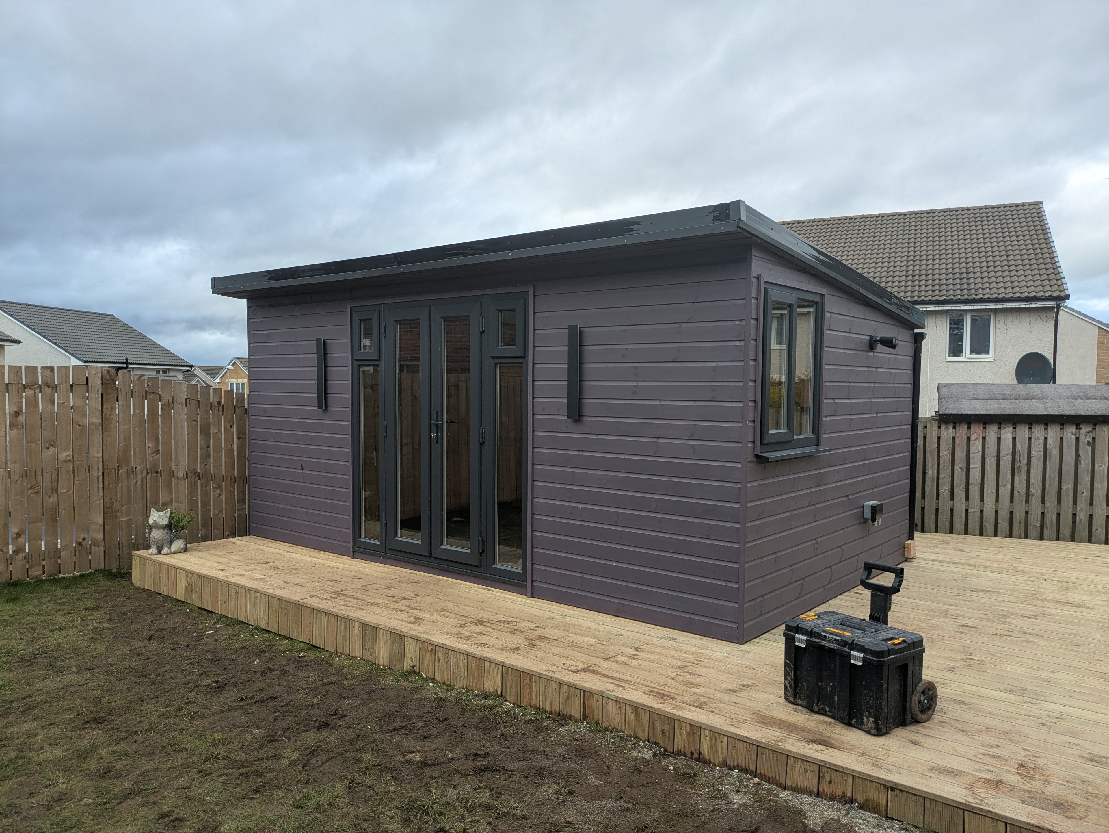 Purple-grey clad garden room with French doors and fresh timber decking