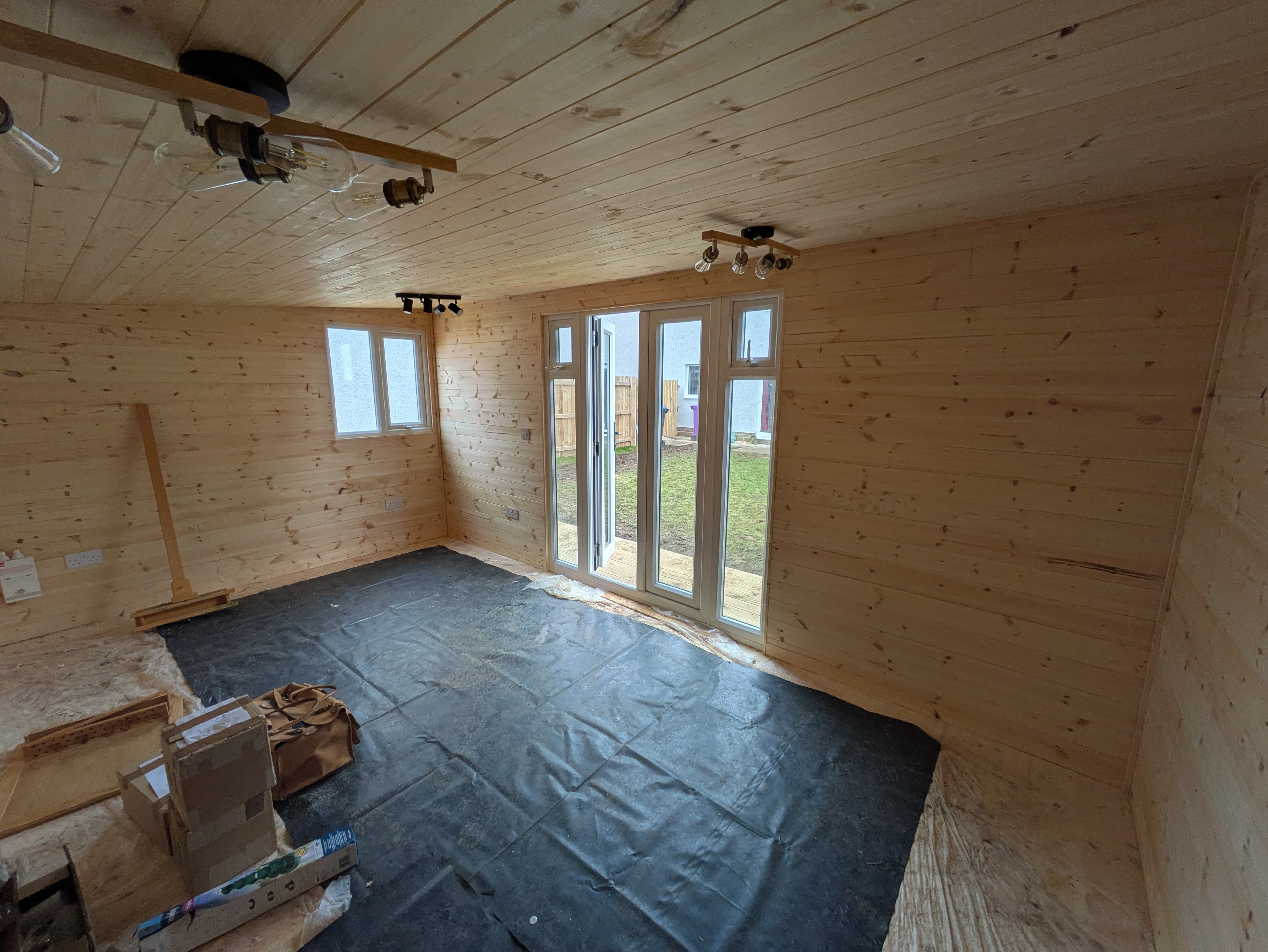 Timber-lined garden room interior with bi-fold doors and spotlights