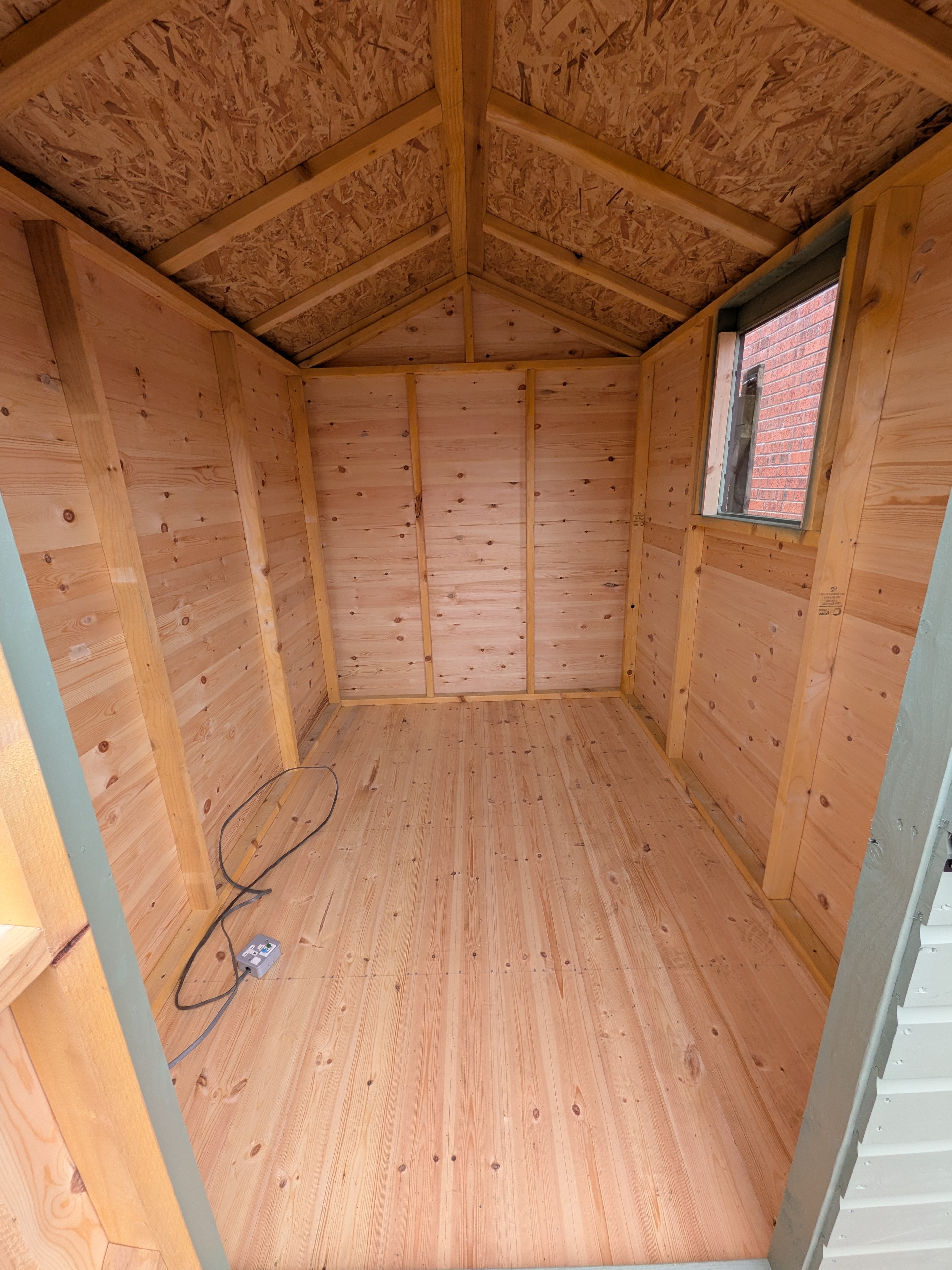 Clean timber shed interior with vaulted roof and window